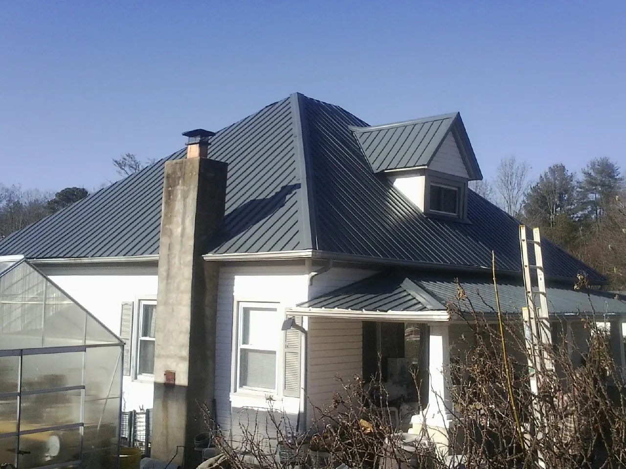 Dark blue standing seam metal roof on a white farmhouse with dormer — Slate & Tile Roof Repair by Roofing Brothers in Mount Tabor