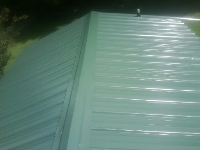 New green metal panels meeting at the ridge of a roof — Flat Roof Repair work by our crew in Mount Tabor