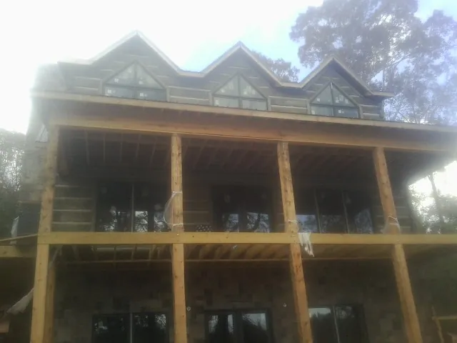 Dormers and porch framing on a large log home under construction — Roof Coating work by our crew in Mount Tabor
