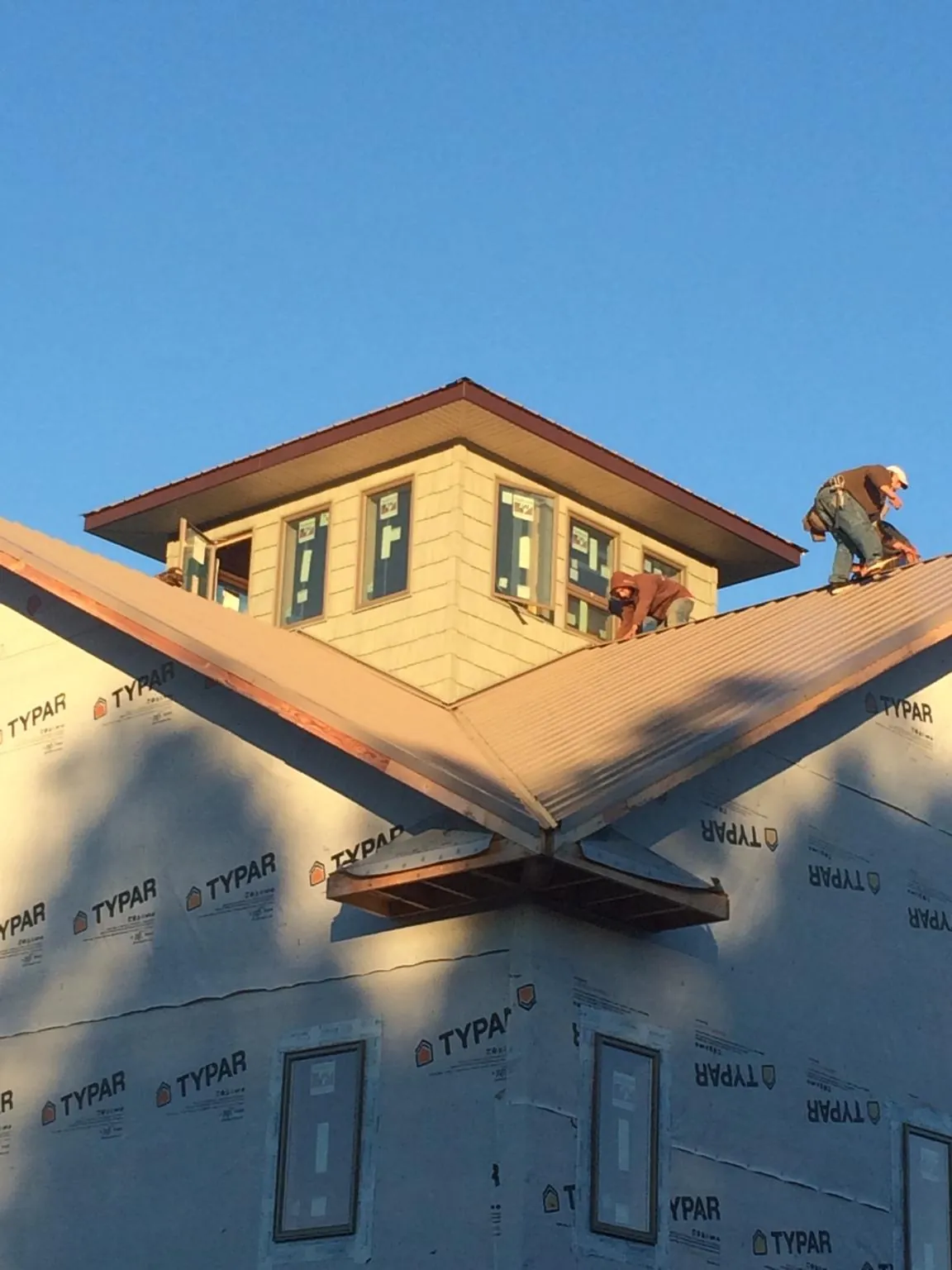 Roofers working around a rooftop cupola on a new metal roof at sunset — Roof Waterproofing in Mount Tabor by Roofing Brothers